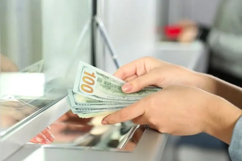 Kunde zählt Dollarscheine an einem Bankschalter