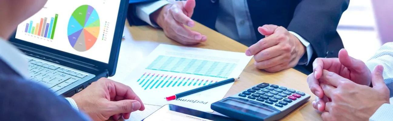 Menschen besprechen Finanzdiagramme an einem Schreibtisch mit Taschenrechner