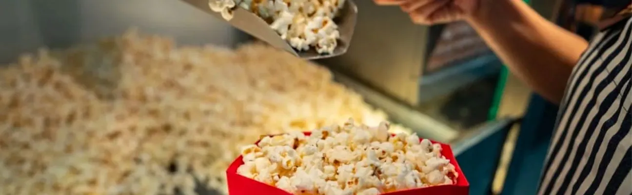 Popcorn wird an der Snacktheke eines Kinos in eine Tüte geschaufelt