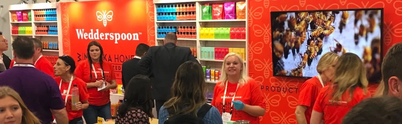Messestand mit einem großen Bildschirm und Personal in orangefarbenen Shirts