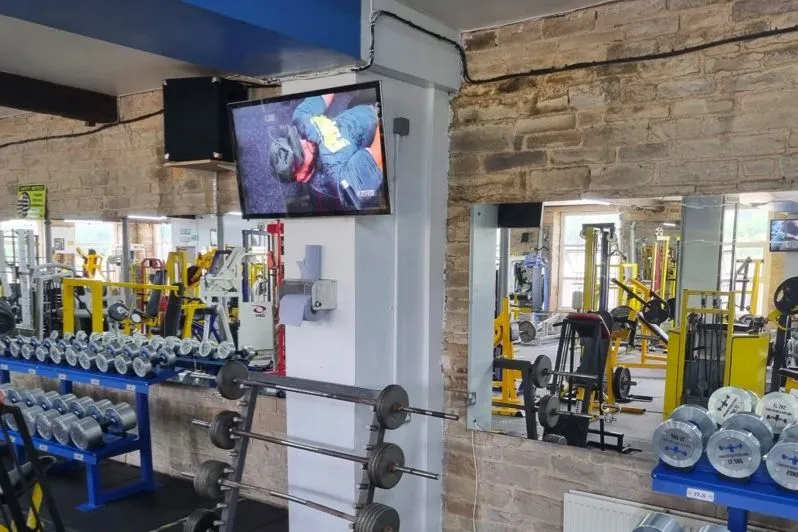 Bildschirm mit einem Trainingsvideo über einem Freihantelbereich