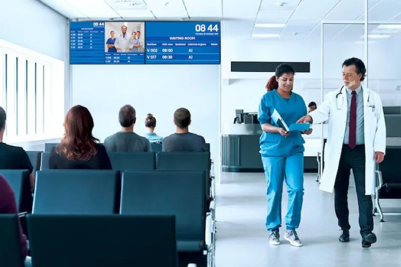Wartebereich eines Krankenhauses mit Bildschirmen über den Sitzen
