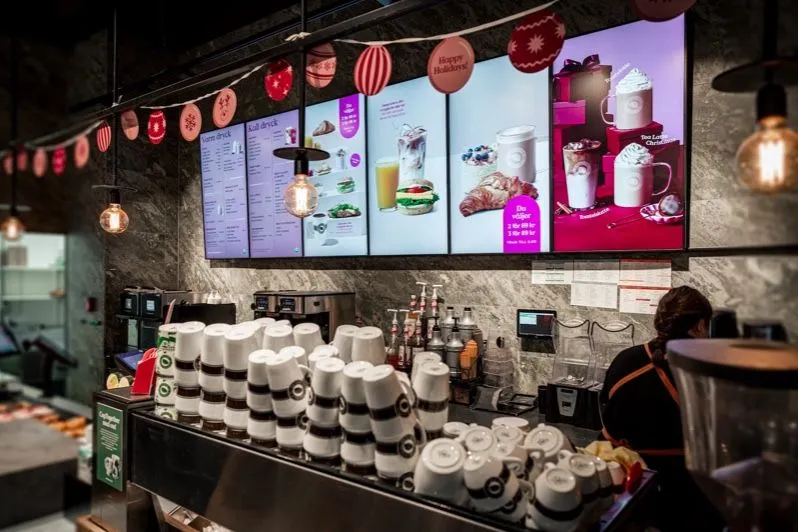 Theke eines Cafés mit einer Reihe digitaler Menübildschirme