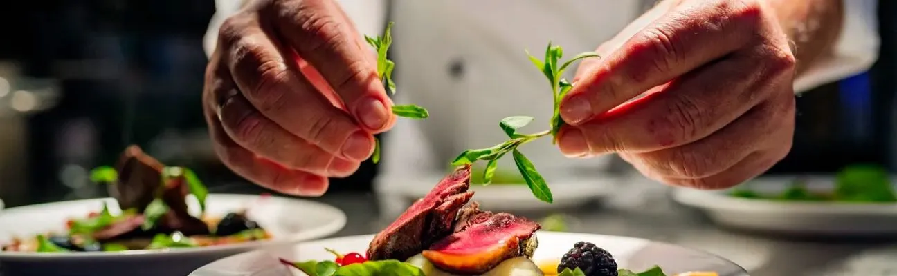 Koch richtet in einer Restaurantküche ein Gericht an
